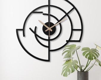 Può includere: Orologio da parete geometrico nero e dorato con un design moderno. L'orologio ha una forma circolare con una cornice in metallo nero e lancette dorate.