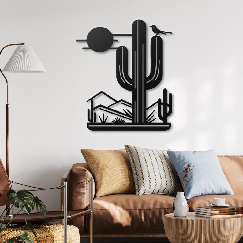 May include: Black metal wall art depicting a desert landscape with a large cactus, a small bird perched on top, and a sun in the background.