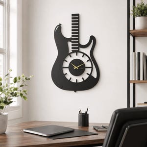 K&ouml;nnte beinhalten: Eine mattschwarze Wanduhr in Form einer E-Gitarre. Die Uhr verf&uuml;gt &uuml;ber einen langen Hals, einen runden Korpus mit ausgeschnittenen Bundmarkierungen sowie d&uuml;nne goldfarbene Stunden- und Minutenzeiger in der Mitte des Zifferblatts.