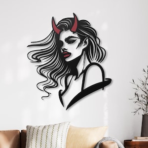 May include: Black and white silhouette of a woman with red horns, her hair flowing behind her. The silhouette is cut out of metal and mounted on a white wall.