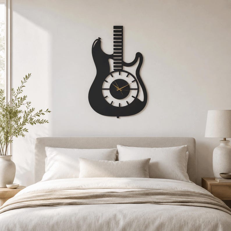 K&ouml;nnte beinhalten: Eine mattschwarze Wanduhr in Form einer E-Gitarren-Silhouette. Das Zifferblatt ist kreisf&ouml;rmig in der Mitte des Gitarrenk&ouml;rpers angebracht und verf&uuml;gt &uuml;ber d&uuml;nne wei&szlig;e Stundenmarkierungen sowie schmale goldfarbene Stunden-, Minuten- und Sekundenzeiger.