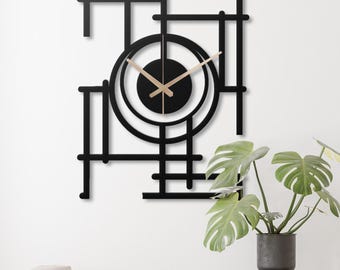 Könnte beinhalten: Schwarze Wanduhr aus Metall mit geometrischem Design. Das Zifferblatt der Uhr ist ein schwarzer Kreis mit goldenen Zeigern.