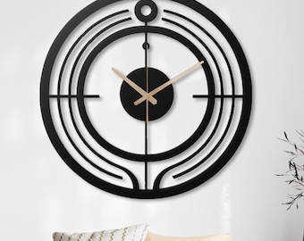 May include: A large black metal wall clock with a geometric design. The clock has a circular face with a smaller circle in the center. The hands are made of wood and are pointing to the time.