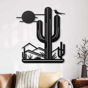 May include: Black metal wall art featuring a desert scene with a large cactus, a small bird perched on top, and a stylised sun in the background.