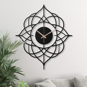 May include: Black metal wall clock with a geometric design. The clock face is black with gold hands.