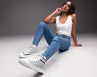 May include: White high-top sneakers with a black and white checkered pattern. The sneakers are paired with blue jeans and a white tank top. The shoes have a unique design, and the overall look is casual and stylish.