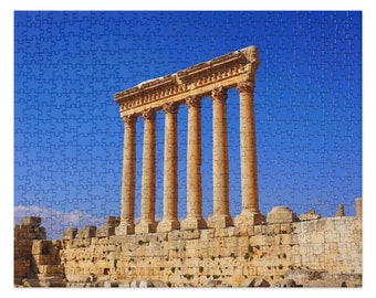 May include: A view of the ancient Roman ruins of the Temple of Bacchus in Baalbek, Lebanon. The temple is made of large stone blocks and has six columns standing tall against a bright blue sky.