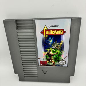May include: A grey Nintendo Entertainment System game cartridge for Castlevania. The label features the Konami logo, a blue-skinned vampire, a castle, and a character wielding a whip. The Nintendo Seal of Quality is visible in the bottom right corner.