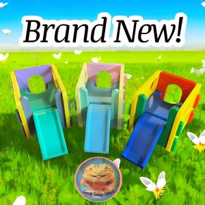 Può includere: Tre strutture da gioco in plastica colorate per piccoli animali, ognuna con uno scivolo. Le strutture sono gialle, rosa e blu con scivoli verdi, blu e blu chiaro. Le strutture sono su una superficie erbosa verde con un adesivo a forma di farfalla bianca nell'angolo in basso a destra dell'immagine. Il testo "Brand New!" è nella parte superiore dell'immagine.