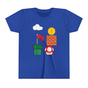 May include: Royal blue t-shirt featuring a colorful graphic design. The design includes a white cloud, a gold coin, a red flag, a green pipe, a red mushroom, and a brick wall. The shirt is made of a soft, comfortable material.