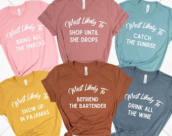 May include: Set of six t-shirts with the text "Most Likely To" followed by a different phrase on each shirt. The shirts are in various colors, including pink, brown, blue, and yellow.