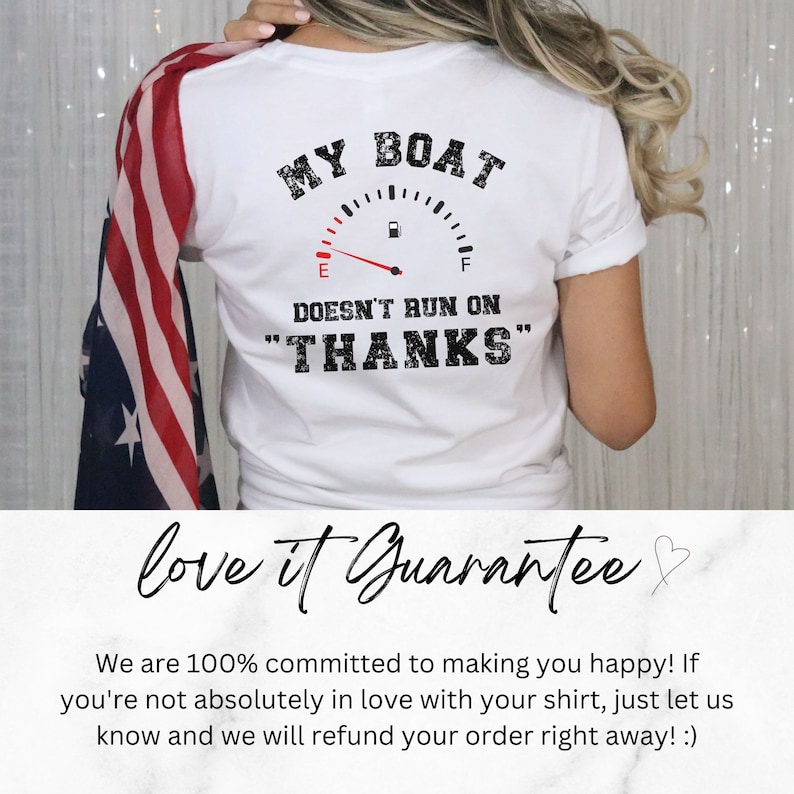May include: White t-shirt with a graphic of a gas gauge that reads "MY BOAT DOESN'T RUN ON "THANKS"". The shirt is being worn by a person with a red, white, and blue scarf.