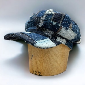 May include: A blue and white patchwork baseball cap with a curved brim. The cap is made of different pieces of fabric sewn together.