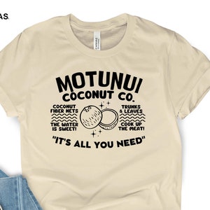 May include: A beige t-shirt with a black graphic design that says "Motunui Coconut Co." with a drawing of two coconuts and the text "Coconut fiber nets, the water is sweet! Trunks & leaves, cook up the meat! "It's all you need."