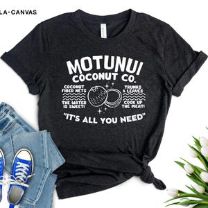 May include: A dark gray t-shirt with white text that reads "Motunui Coconut Co." and includes a graphic of coconuts. The text also says "Coconut fiber nets, the water is sweet! Trunks & leaves, cook up the meat!" and "It's all you need."