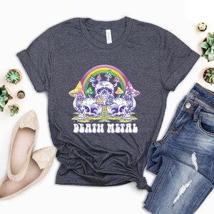 May include: A dark heather grey t-shirt with a graphic of a rainbow, mushrooms, and skulls. The text "Death Metal" is printed in a retro font below the graphic.