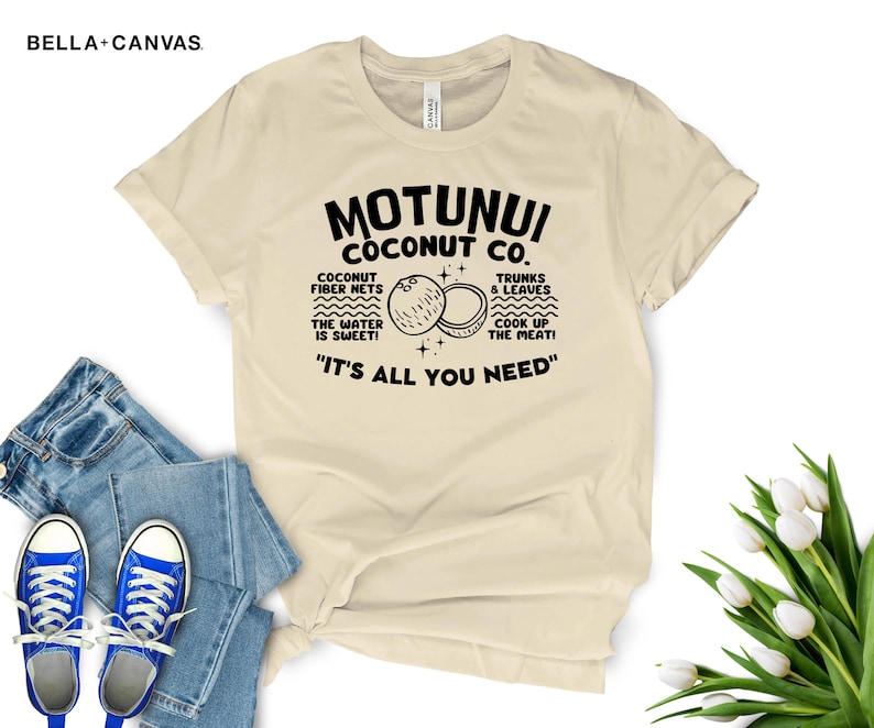 May include: A beige t-shirt with a black graphic design that says "Motunui Coconut Co." with a drawing of two coconuts and the text "Coconut fiber nets, the water is sweet! Trunks & leaves, cook up the meat! "It's all you need."