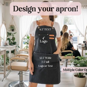 May include: A dark gray apron with leather accents and pockets. The apron is 12.5 inches wide and 7.5 inches tall, with space for a 4-inch logo and 6.5 inches of text. The text "Design your apron!" is displayed at the top. Multiple color options are available.