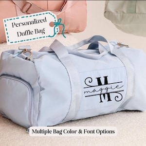 May include: Light blue personalized duffel bag with a black monogram that says "Maggie". The bag has a zipper closure and a side pocket. Multiple bag color and font options are available.
