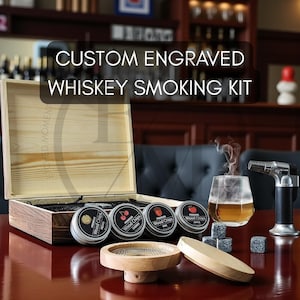 May include: A custom engraved whiskey smoking kit with a wooden box, various wood chip tins, a glass of whiskey, and a torch lighter. The kit includes a wooden smoking base and whiskey stones. The text on the box reads "CUSTOM ENGRAVED WHISKEY SMOKING KIT."