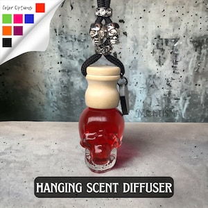 May include: Red glass skull-shaped hanging car air freshener with a wooden cap and a black cord with silver skull charms.  The air freshener is labeled "Hanging Scent Diffuser".
