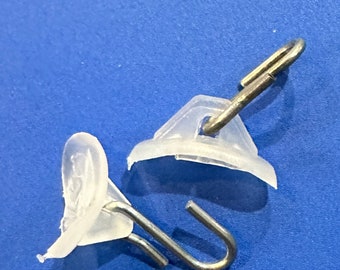 May include: Two clear plastic curtain hooks with metal hooks. The hooks are designed to be used with a curtain rod.