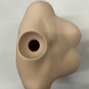 May include: A beige mannequin torso with a round hole in the center. The torso is smooth and has a slightly rounded shape.