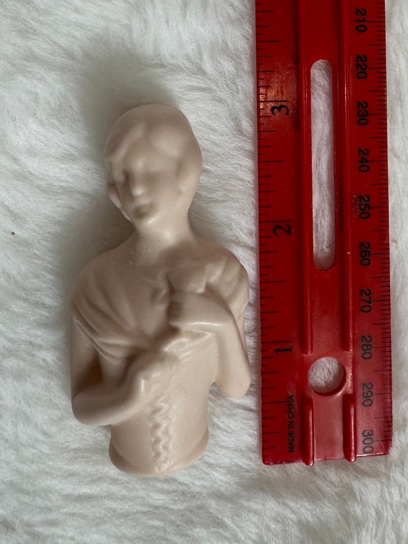 Może przedstawiać: Porcelanowa figurka kobiety w białej sukni z delikatnym wzorem kwiatowym. Figurka ma około 15 cm wysokości.