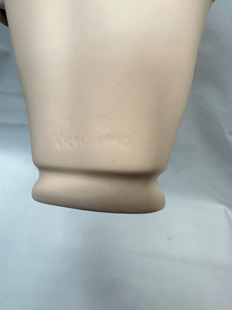 May include: A white ceramic figurine with the words "Vicki Russo" inscribed on the bottom.