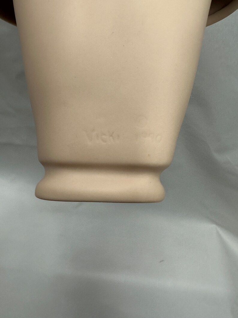 May include: Close-up of the bottom of a white ceramic mannequin head with the text "Vicky Pro" inscribed on the bottom.