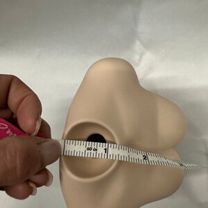 May include: A light brown ceramic bust with a round opening at the top, measured with a tape measure that reads "60 in".