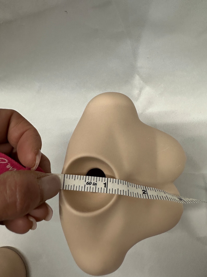 May include: A light brown ceramic bust with a round opening at the top, measured with a tape measure that reads "60 in".