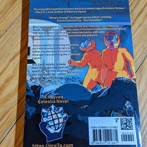 Op de afbeelding: Een sciencefiction-boekomslag met twee personages in oranje ruimtepakken met helmen op een donkere achtergrond. De titel van het boek is "A Hayven Celestia Novel" en de tekst "What's wrong?" is zichtbaar. Het ISBN van het boek is 9798631121881.