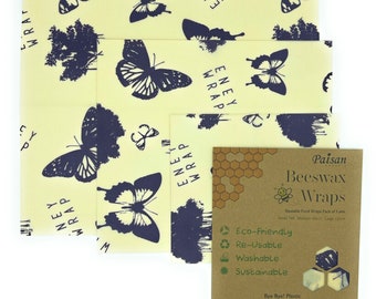 May include: A set of three beeswax food wraps with a butterfly and tree pattern. The wraps are reusable, washable, and sustainable. The packaging is brown with the text "Paisan Beeswax Wraps" and a bee illustration.