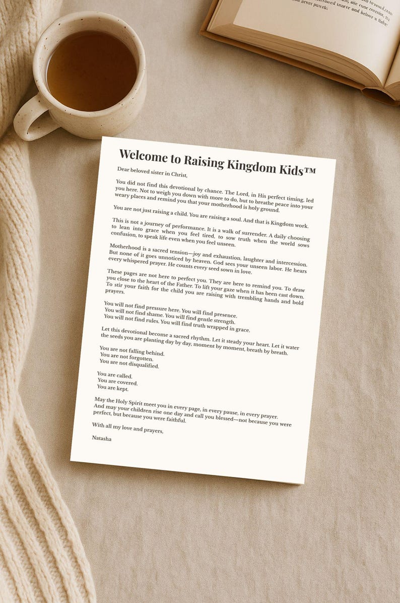 May include: A devotional titled "Welcome to Raising Kingdom Kids&trade;" with text on a white paper. A cup of tea sits to the left. The text is in black font. The devotional is on a cream-colored surface.