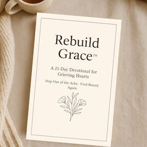 Op de afbeelding: Een crèmekleurige kaart met de titel "Rebuild Grace" en de ondertitel "A 21-Day Devotional for Grieving Hearts". De kaart heeft een bloemenillustratie en de tekst "Step Out of the Ache. Find Beauty Again." Een kopje thee en een boek staan op de achtergrond.