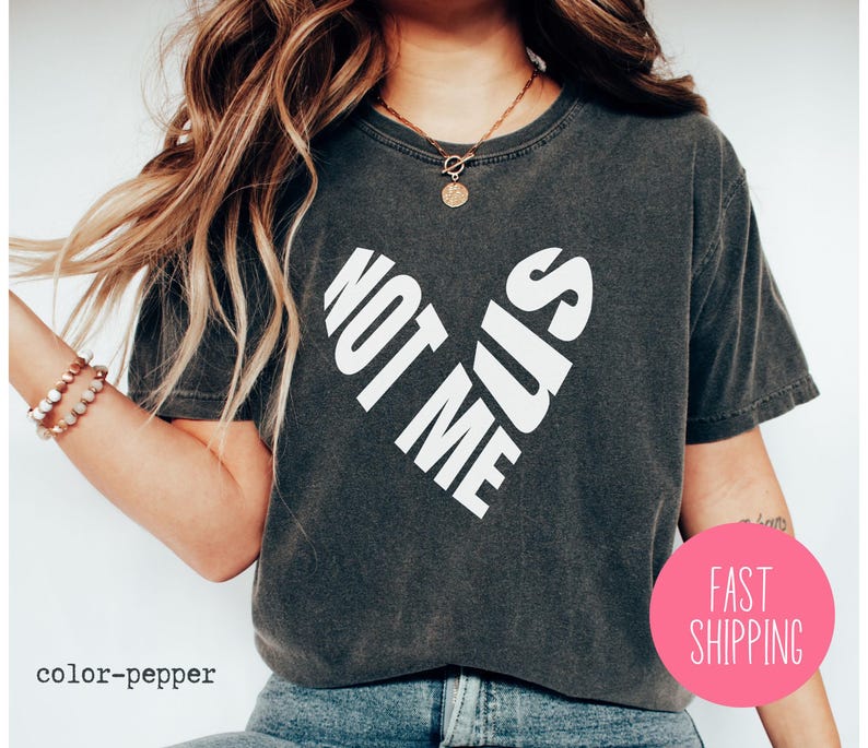 May include: A dark gray cropped t-shirt with a white graphic that says "Not Me Sis" in a heart shape.