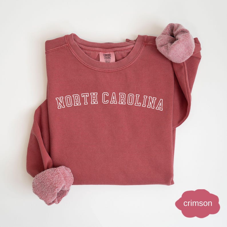 May include: A crimson red sweatshirt with the text "NORTH CAROLINA" in white outlined letters.