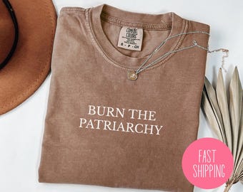 May include: A brown t-shirt with the text "BURN THE PATRIARCHY" printed in white. The shirt is made of a soft, comfortable material and has a distressed look.