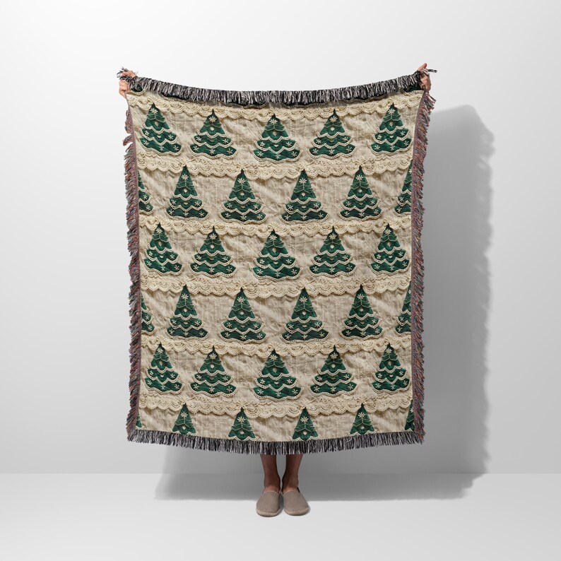 May include: A cream-colored woven throw blanket with a repeating pattern of green Christmas trees. The blanket has a fringe border.