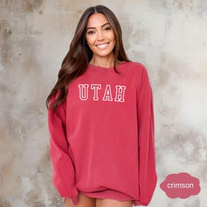 May include: A crimson red sweatshirt with the word "UTAH" printed in white on the front.