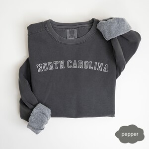May include: A dark gray sweatshirt with the text "NORTH CAROLINA" in white outlined letters.
