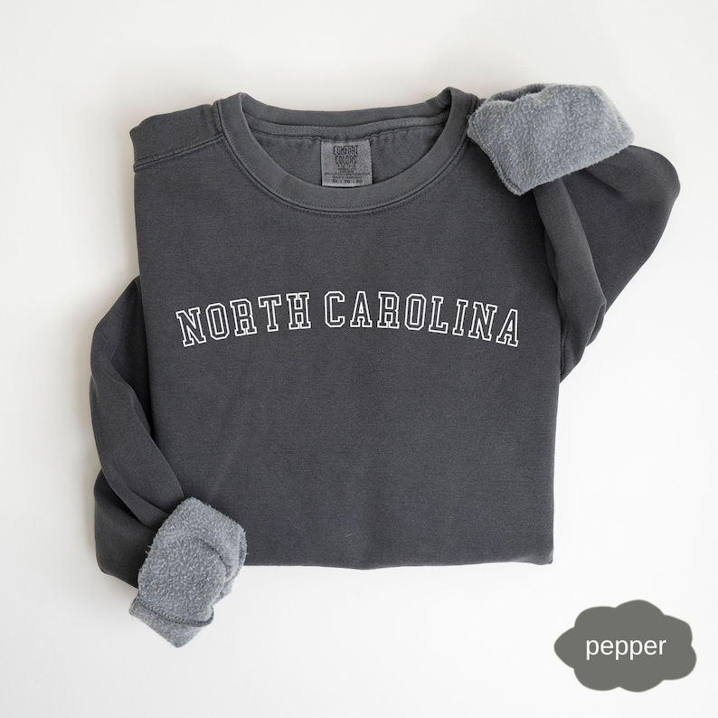 May include: A dark gray sweatshirt with the text "NORTH CAROLINA" in white outlined letters.