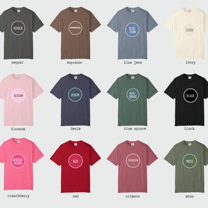 K&ouml;nnte beinhalten: Eine Kollektion von zw&ouml;lf kurz&auml;rmeligen T-Shirts in verschiedenen Farben, jedes mit einem kreisf&ouml;rmigen Design in der Mitte. Die Farben sind Pfeffer, Espresso, Blue Jean, Elfenbein, Blossom, Denim, Blue Spruce, Schwarz, Crunchberry, Rot, Karmesinrot und Moos.