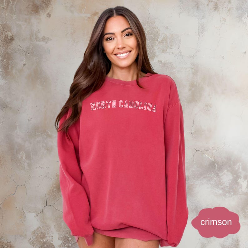 May include: A crimson red sweatshirt with the text "NORTH CAROLINA" in white outlined letters.
