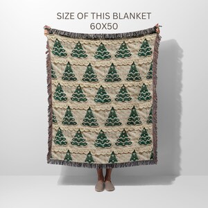 May include: A cream-colored throw blanket with a green Christmas tree pattern. The blanket is 60 inches by 50 inches.
