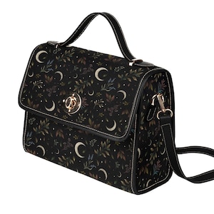May include: A black satchel-style handbag with a flap closure, featuring a pattern of crescent moons, leaves, and stars. The bag has a top handle and a detachable shoulder strap. Gold-colored hardware accents the bag's design.