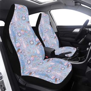 May include: Two car seat covers with a light blue background and a repeating pattern of witchy elements. The pattern includes potion bottles, hands, skulls, moons, and books. The seat covers have black borders.