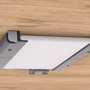 May include: A grey and black wall-mounted tablet holder with a white tablet. The holder has a simple design and is made of sturdy materials.