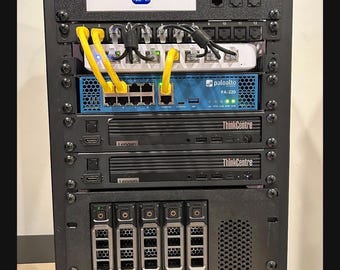 Op de afbeelding: Een zwart serverrack gevuld met netwerkhardware. Het bevat een wit apparaat, een blauwe Palo Alto PA-220, twee Lenovo ThinkCentre-apparaten en verschillende harde schijf bays. Gele en zwarte kabels verbinden de apparaten.
